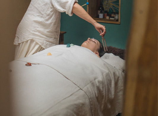 Woman on bed having a treatment with crystals and a tuning fork