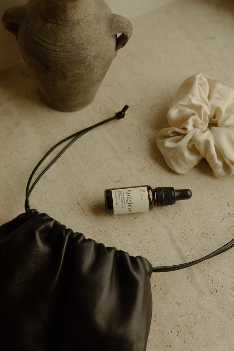 IM_frequency_medicine_enlighten_scrunchie on kitchen bench with vase and satin bag amber bottle white label