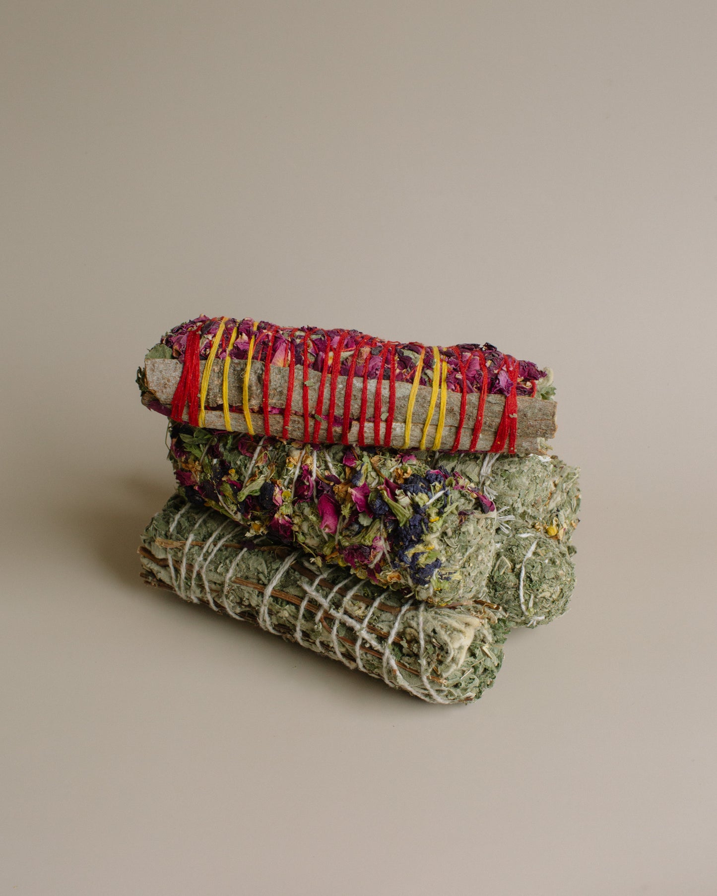 Stack of woven herbal smoke bundles on a beige background