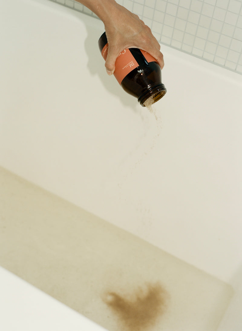 Ground base chakra bath salts jar and bath being poured into bath tub 