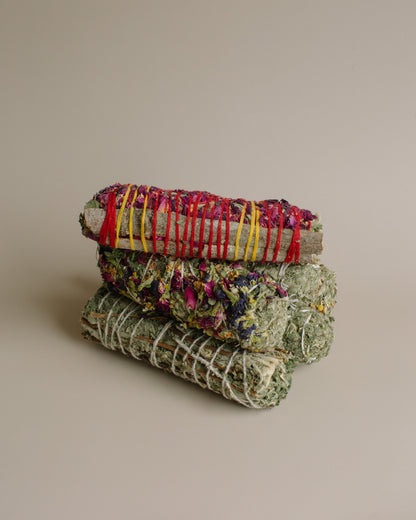 Stack of woven herbal smoke bundles on a beige background